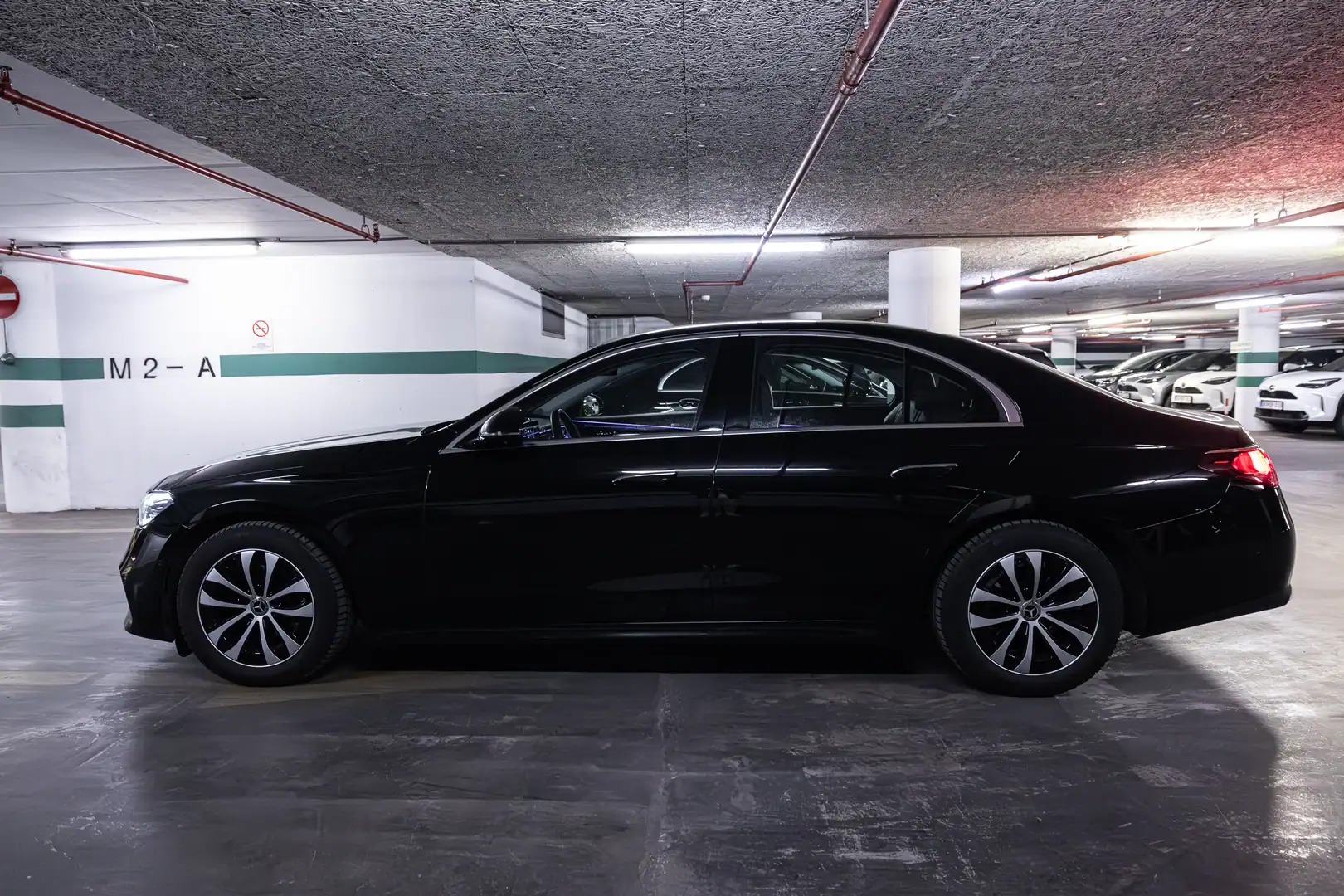 Side profile of a black Mercedes-Benz E-Class sedan parked inside a garage.