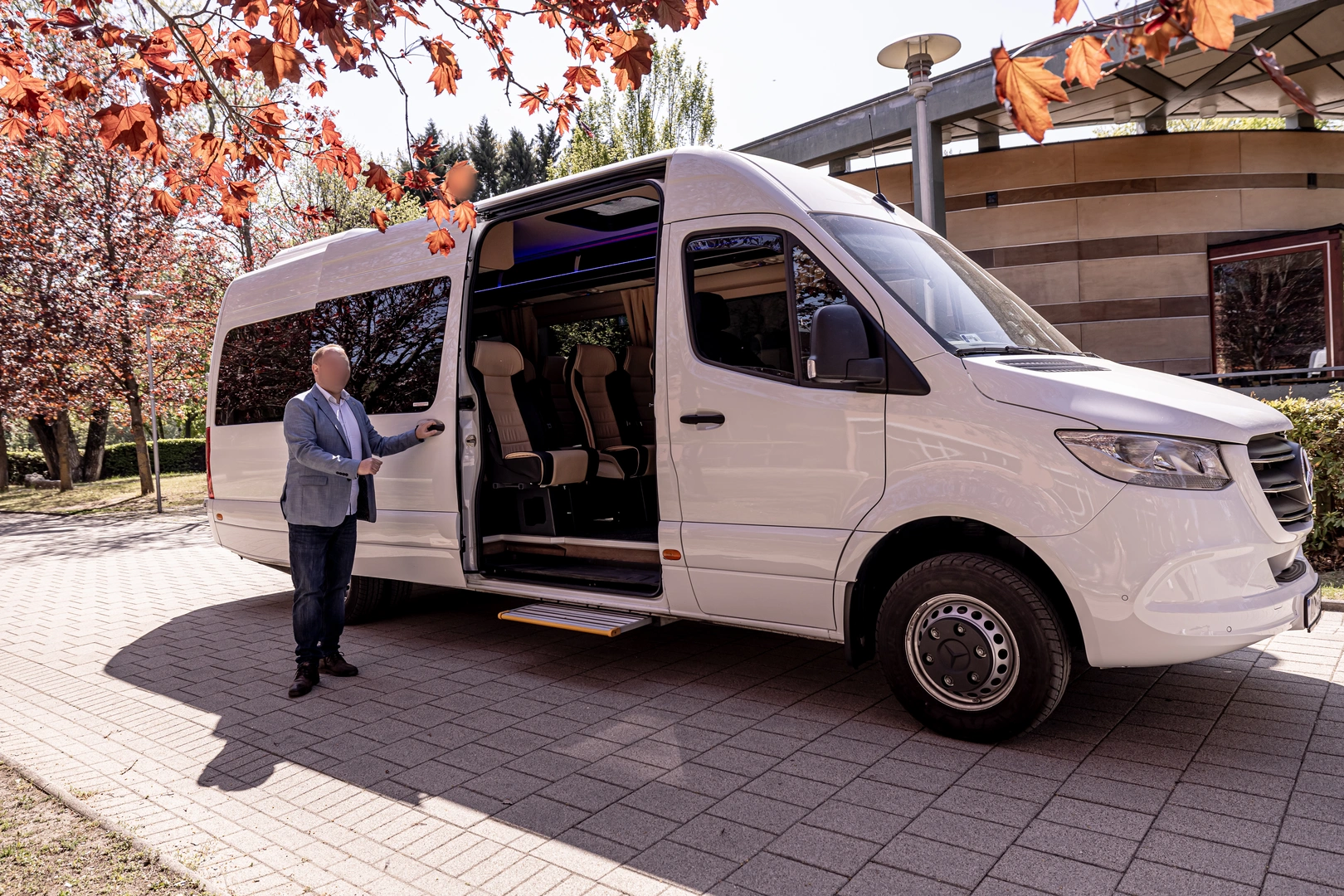 Chauffeur beside a white Mercedes-Benz Sprinter minibus