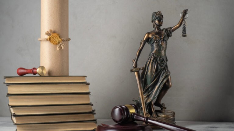 Lady Justice statue with scales, gavel, and law books representing securities law and litigation.
