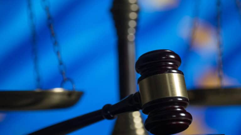 Gavel resting on a table with courtroom scales in the background, symbolizing legal proceedings and.