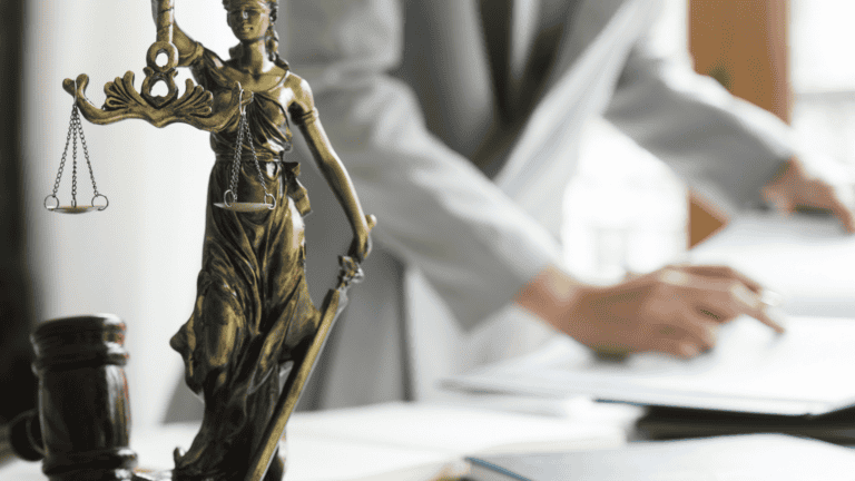 Bronze Lady Justice statue with scales and sword in a legal office setting.