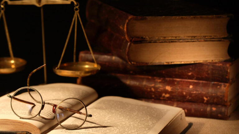 Vintage legal books and scales of justice on a wooden desk.