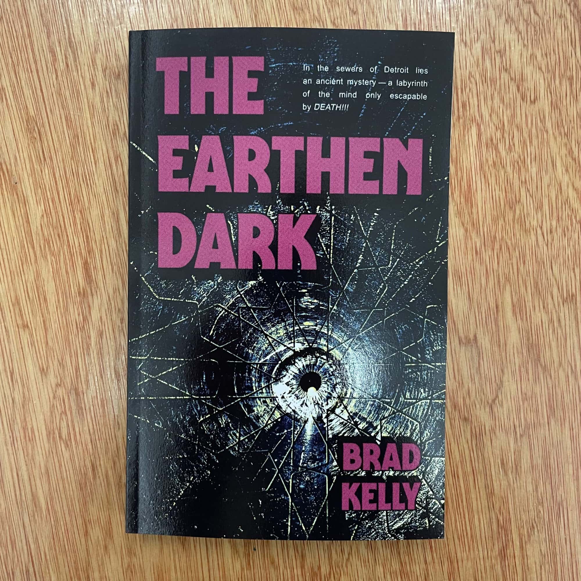 Cover of 'The Earthen Dark' by Brad Kelly featuring a dark, cracked surface with a central hole and purple text.