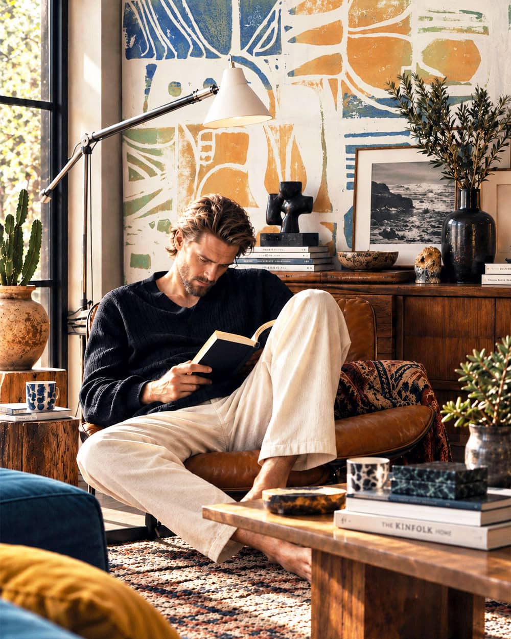 A man reading in front of yellow abstract Vesper Royale wallpaper in a contemporary interior