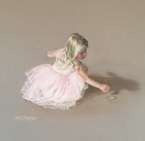 Young girl in pink dress drawing in the sand with pastel colors.