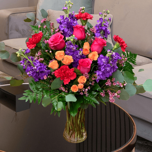 Elegant bouquet of pink roses, purple lisianthus, and orange spray roses for Mother's Day.