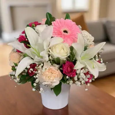 Pink gerbera daisies, white lilies, roses, baby's breath, and lush greenery in a white vase, perfect for elegant flower delivery and special occasions in Las Vegas.