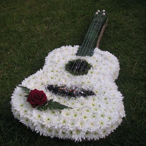 White floral guitar-shaped funeral arrangement with red rose accent for memorial services.