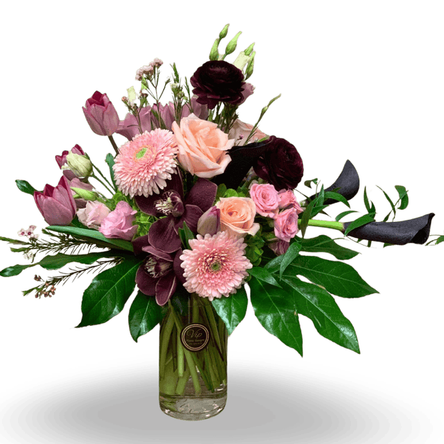 Elegant French Riviera floral arrangement with pink, purple, and peach blooms in a clear glass vase.