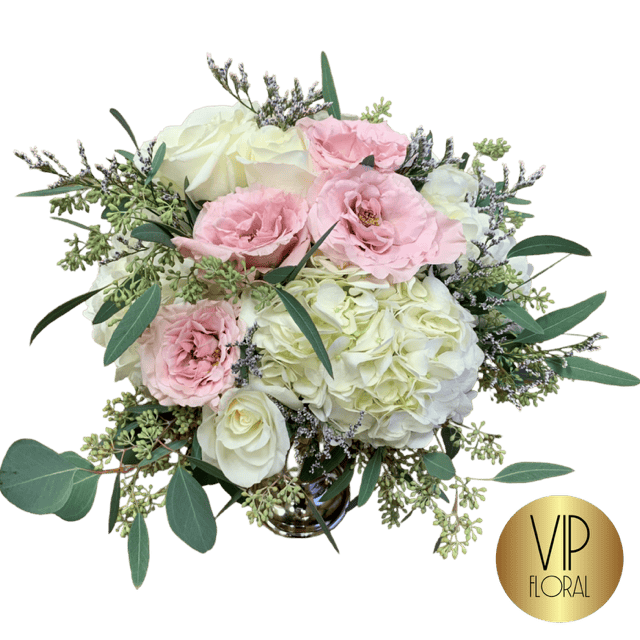 Beautiful floral centerpiece featuring white roses, pink lisianthus, and lush greenery, perfect for elegant occasions and celebrations.