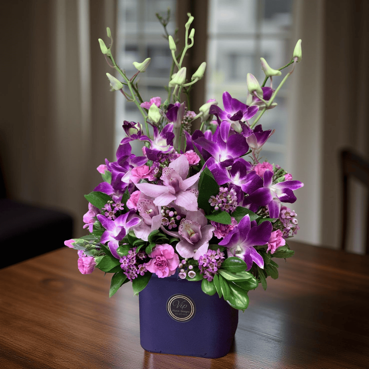 Lavender and pink orchid floral arrangement in a navy blue VIP Floral gift box, perfect for special occasions and flower delivery in Las Vegas.