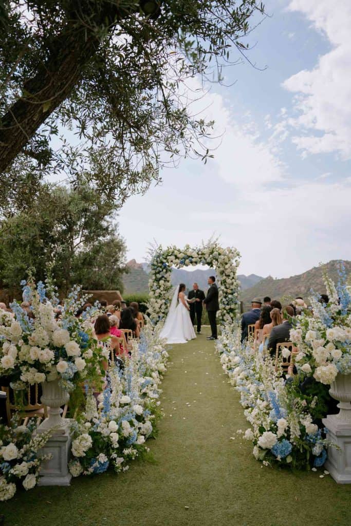 Wedding floral arch with white and blue blooms for outdoor ceremony.