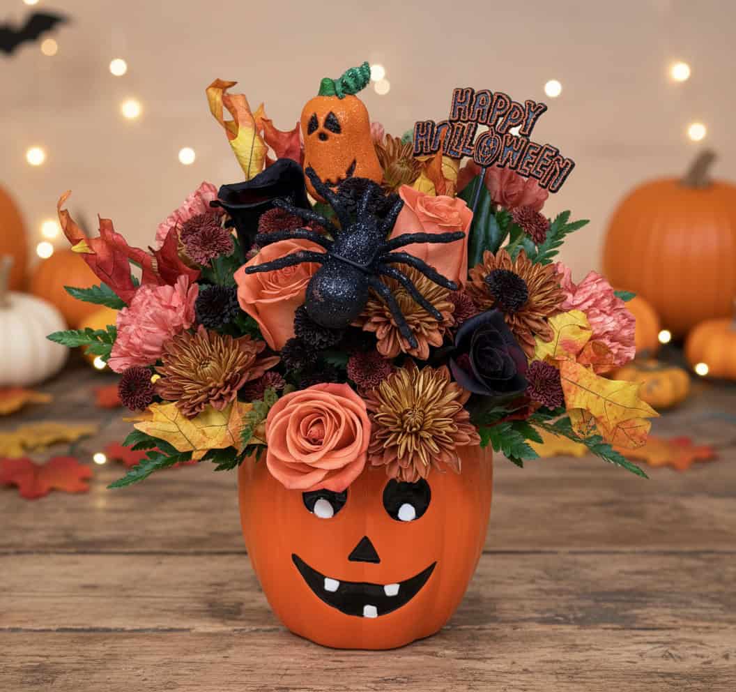 Halloween flower arrangement in jack-o-lantern pumpkin vase with orange roses, burgundy chrysanthemums, black spider, and Happy Halloween pick delivered in Las Vegas