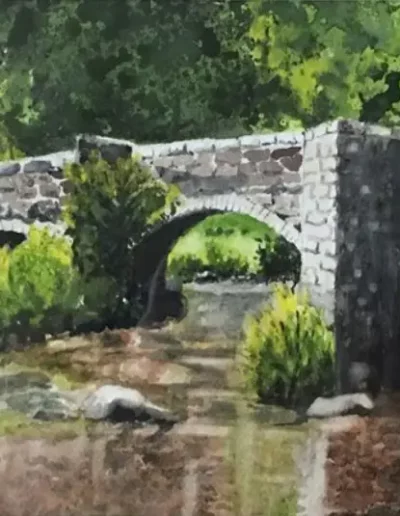 Stone bridge over scenic creek with trees
