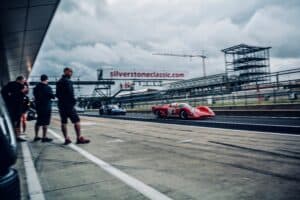 An image of a red coupe racing car leaving the pit lane of Silverstone Racing Circuit in Northamptonshire