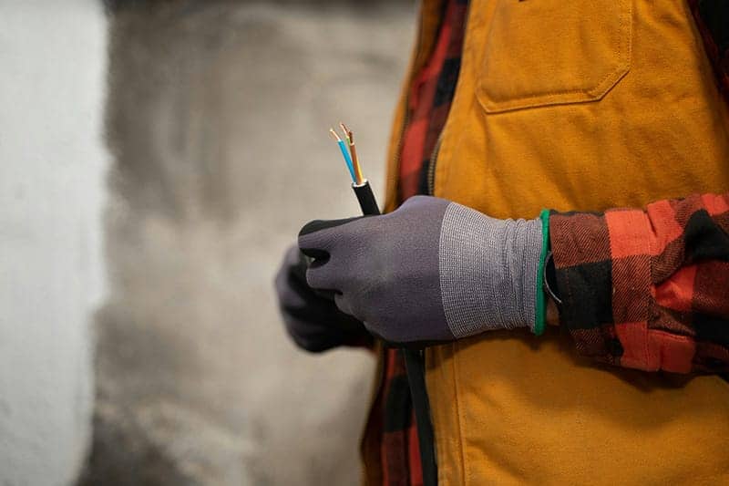 A close up of an electrician's hands stripping cables, exposing the copper wires