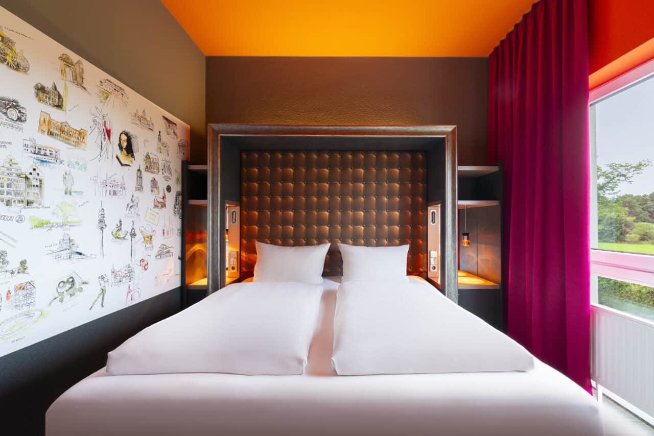 Doppelzimmer – Blickrichtung auf das Bett, rechts Fenster. Doppelbett durchgehend bezogen, Nachttische