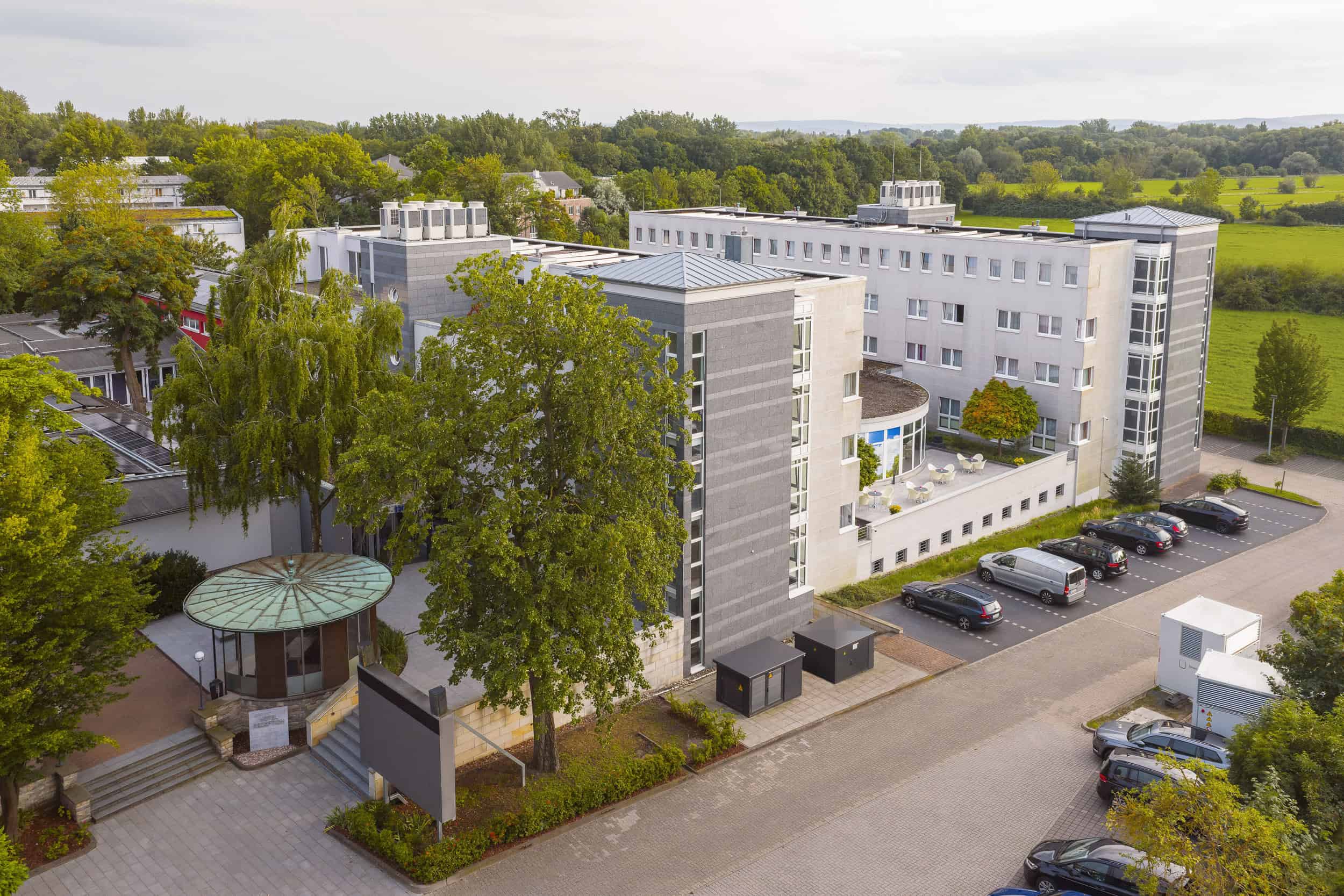 Architektur des Hotel Wiencke XI. als Luftaufnahme, eingebettet von umgebendem Baumbestand