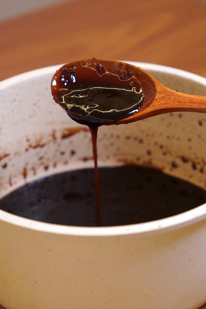 Thick and glossy homemade sweet soy glaze dripping from a spoon