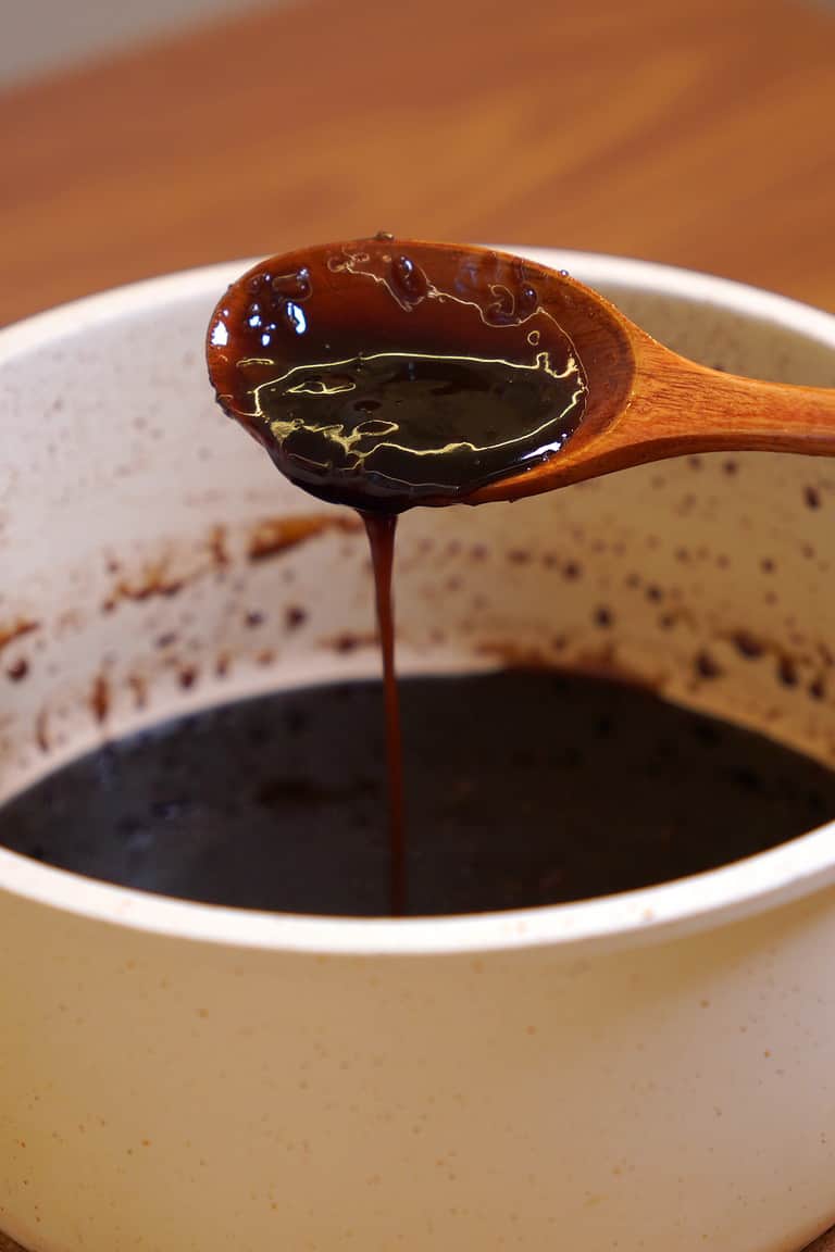 Thick and glossy homemade sweet soy glaze dripping from a spoon