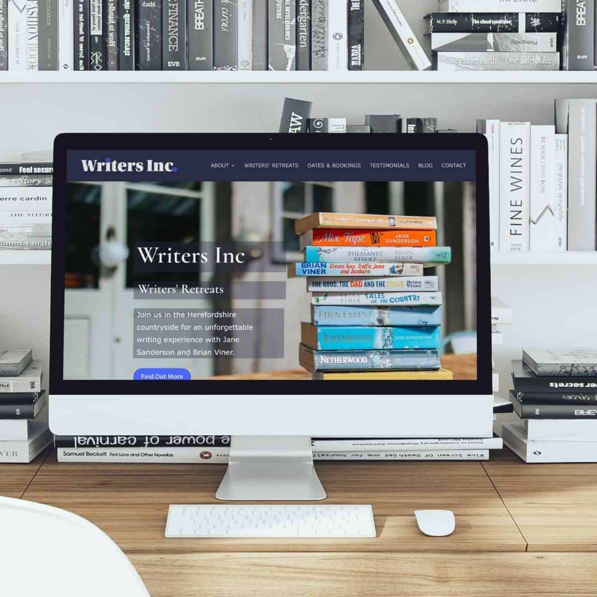 A computer monitor displaying a writers' retreat website with stacked books, on a desk surrounded by.