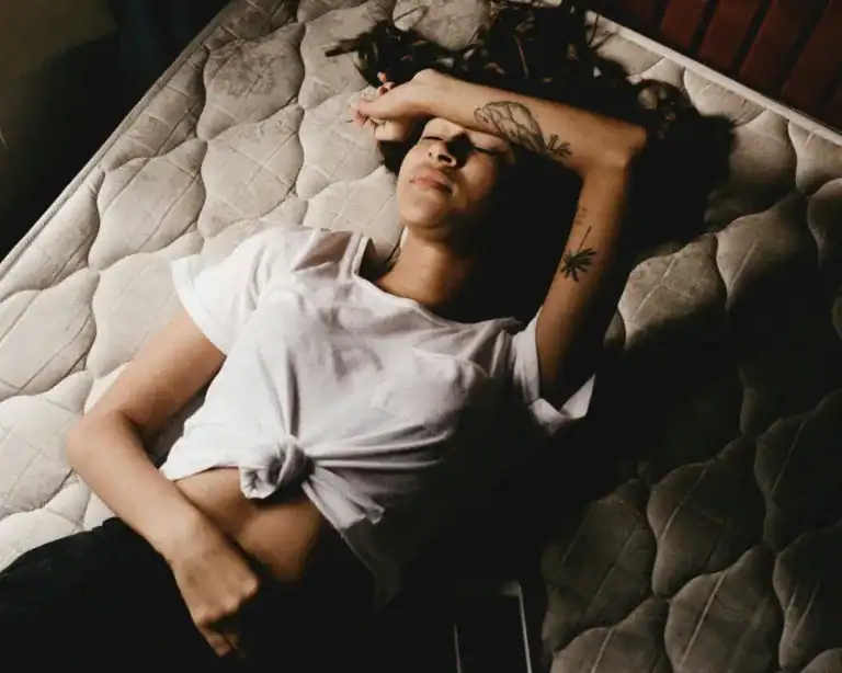 Woman suffering from post menstrual syndrome lies in bed experiencing a headache and cramps