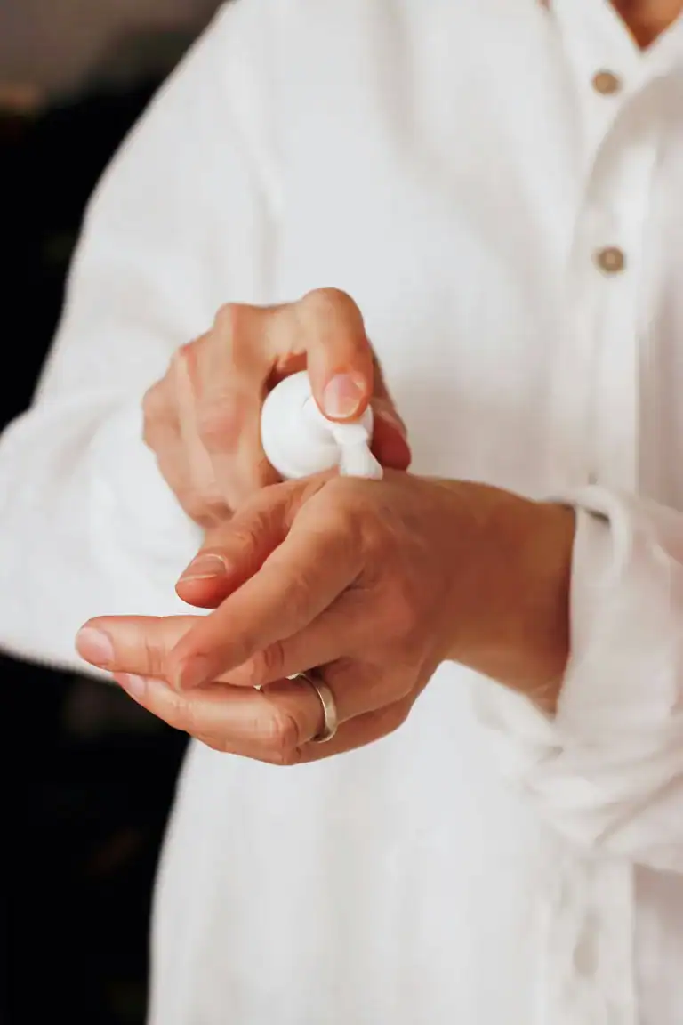 A shot of woman from shoulders down, applying magnesium lotion to her wrist