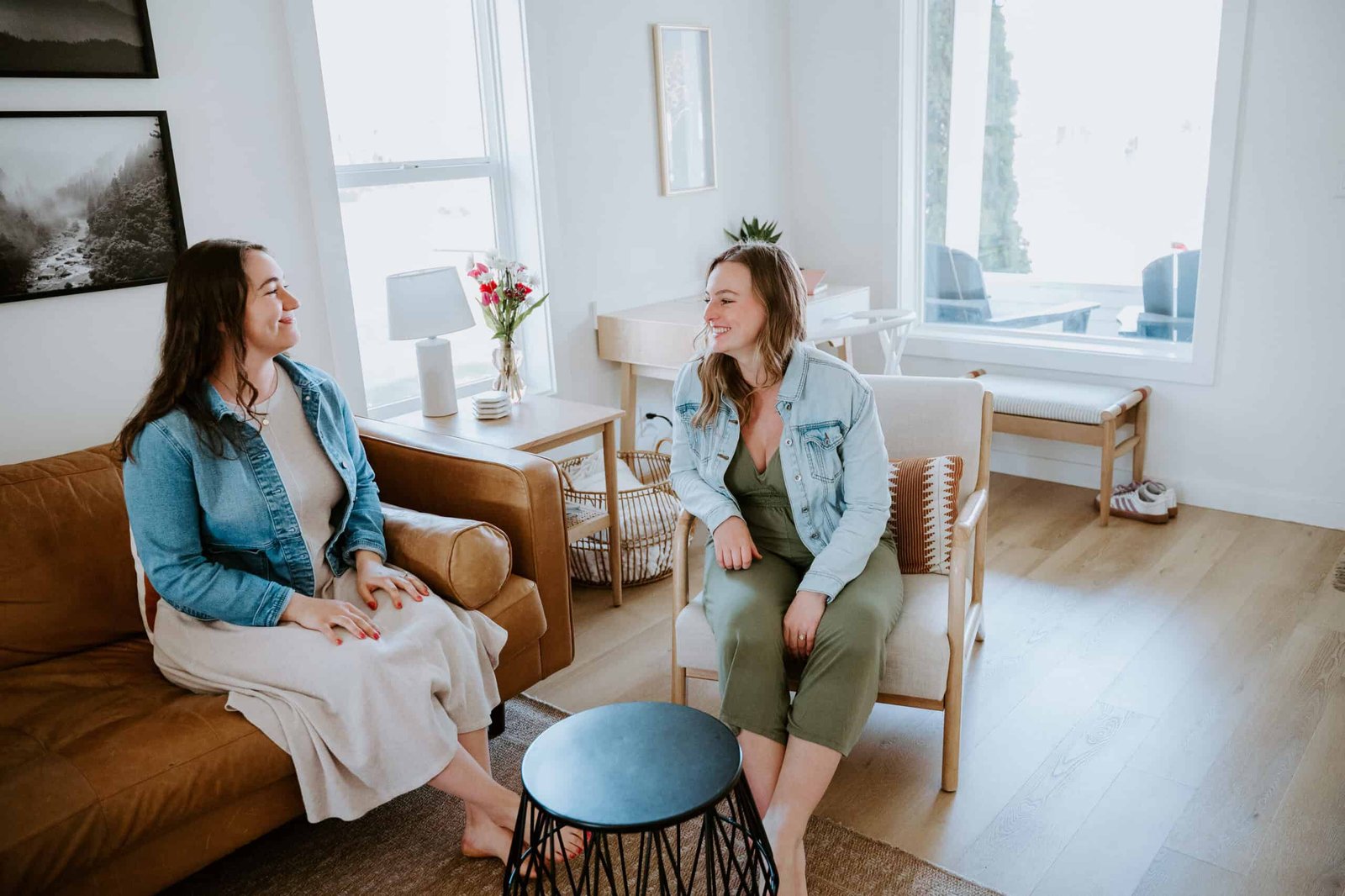 Two women having a friendly conversation in a bright, modern living room.