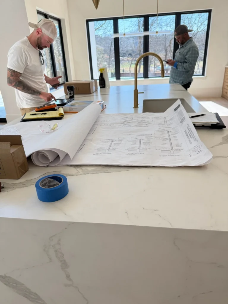 Plans laid out, details verified — our team walks through architectural drawings on-site during a custom home build. Reviewing every wall section, finish, and fixture spec ensures the build matches the design intent before final trim and punch-out.