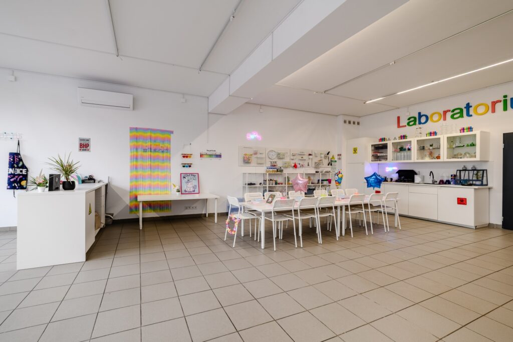 Kolorowa sala laboratoryjna w kreatywnym centrum edukacyjnym z nowoczesnym wystrój, stolikami, różnorodnymi materiałami i akcesoriami do eksperymentów, idealna dla dzieci i młodzieży, edukacja i nauka zabawą.