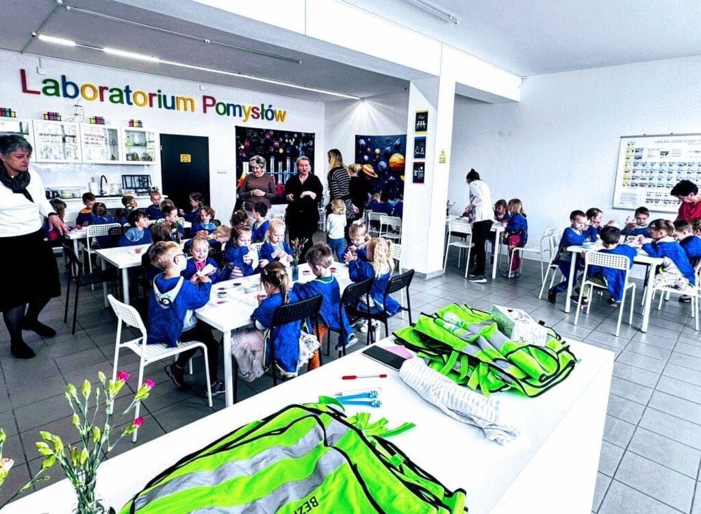 Kolorowe laboratorium pomysłów z grupą dzieci i nauczycielami, przygotowujące się do zajęć edukacyjnych i eksperymentów w innowacyjnej przestrzeni nauki dla dzieci.