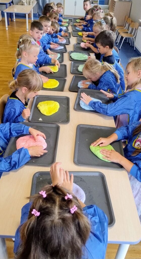 Rysunek dzieci w grupie uczących się lepienia ciast ze squishy na warsztatach w przedszkolu, uczą się kreatywności i sensorycznej zabawy.