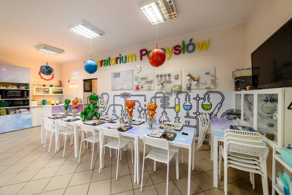 Kolorowa sala do warsztatów w Pracowni Półyśw Przedszkola, dekoracje i pomoce naukowe, przestrzeń do kreatywnych zajęć dla dzieci i edukacji naukowej, wyposażona w nowoczesne akcesoria.