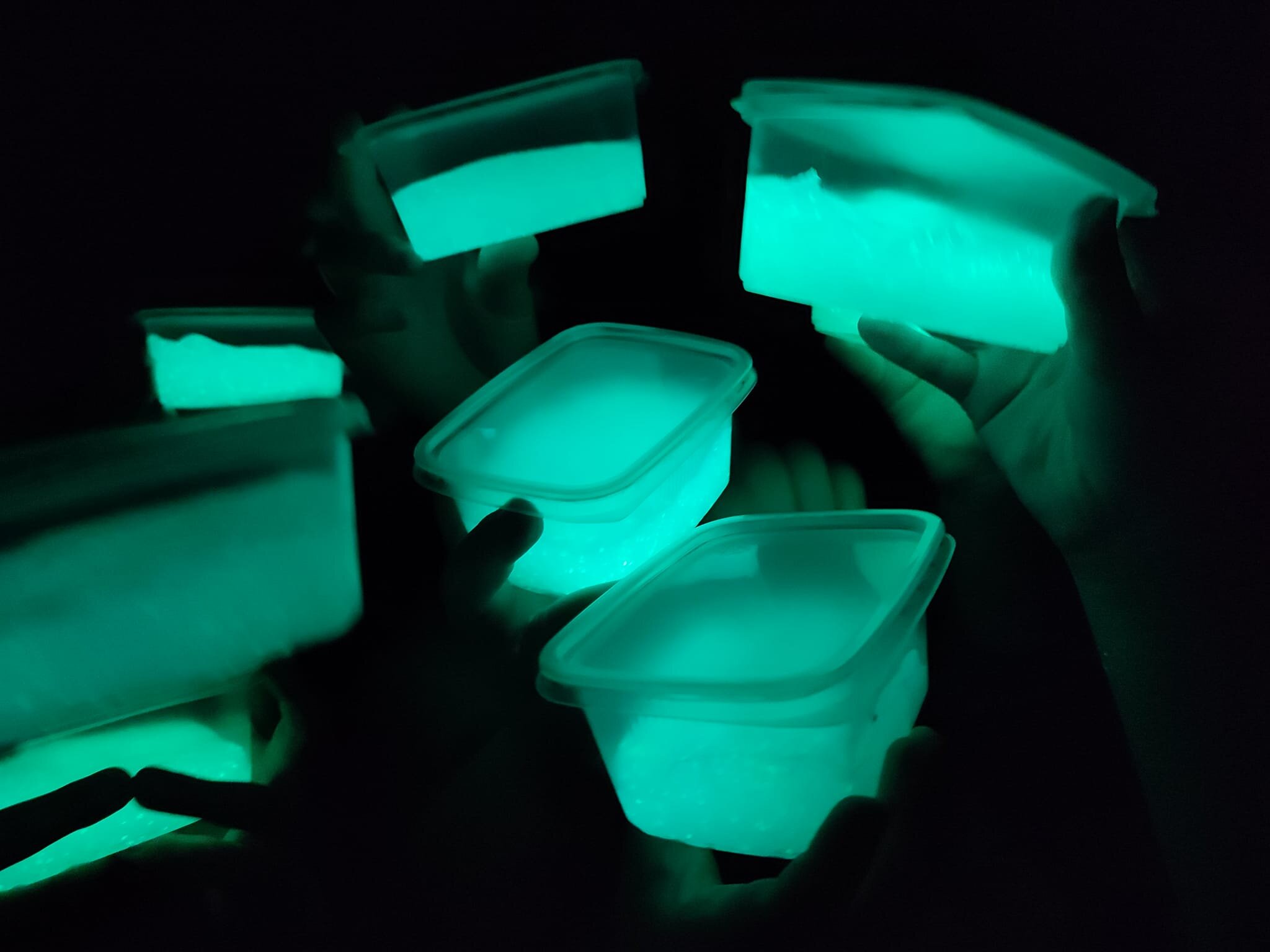 Glow-in-the-dark produkty spożywcze premium, estetycznie pakowane w plastikowe pojemniki, podświetlane fluorescencyjnym światłem, idealne na imprezy i wydarzenia tematyczne.
