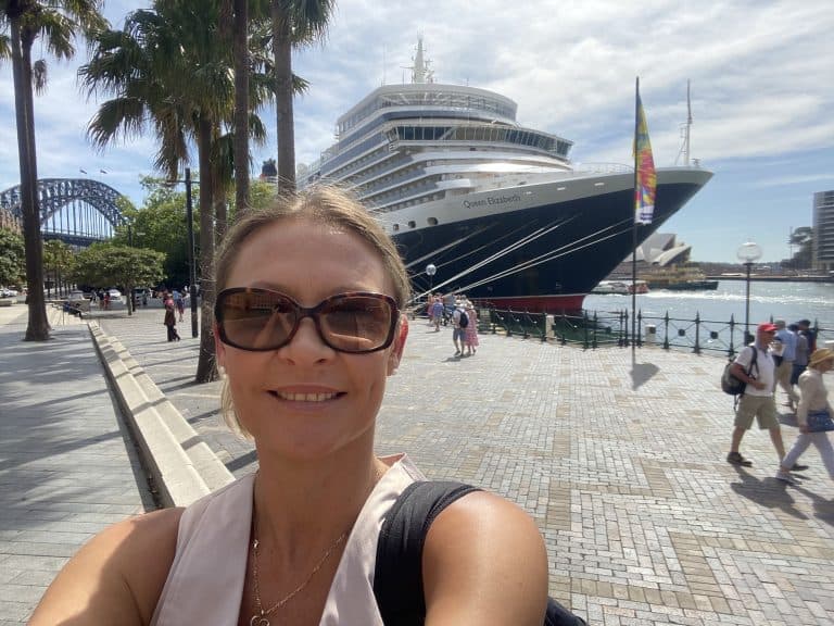 Me standing in front of Cunards Queen Mary 2 in Sydney Australia. The Opera House and Sydney Harbour Bridge are in the background.