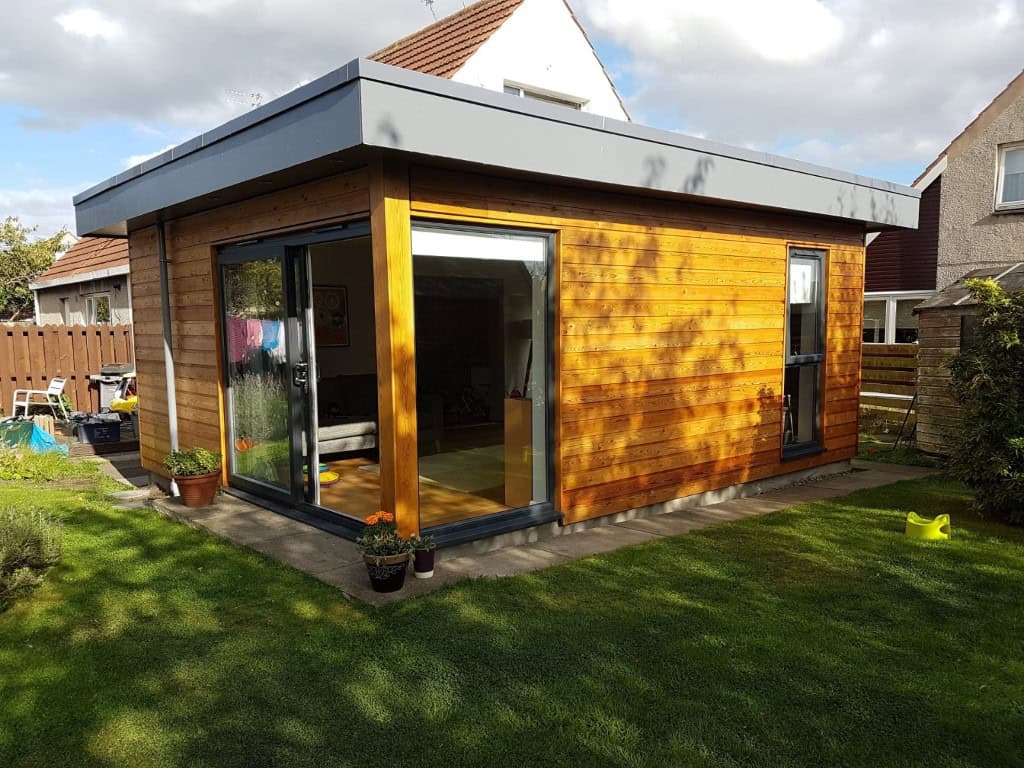 Garden room with wooden cladding, large glass sliding doors, and contemporary flat roof. Perfect outdoor workspace or studio.