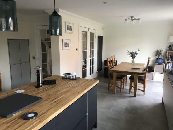 Contemporary kitchen with wooden worktops, chic lighting, and cosy dining space for family gatherings.