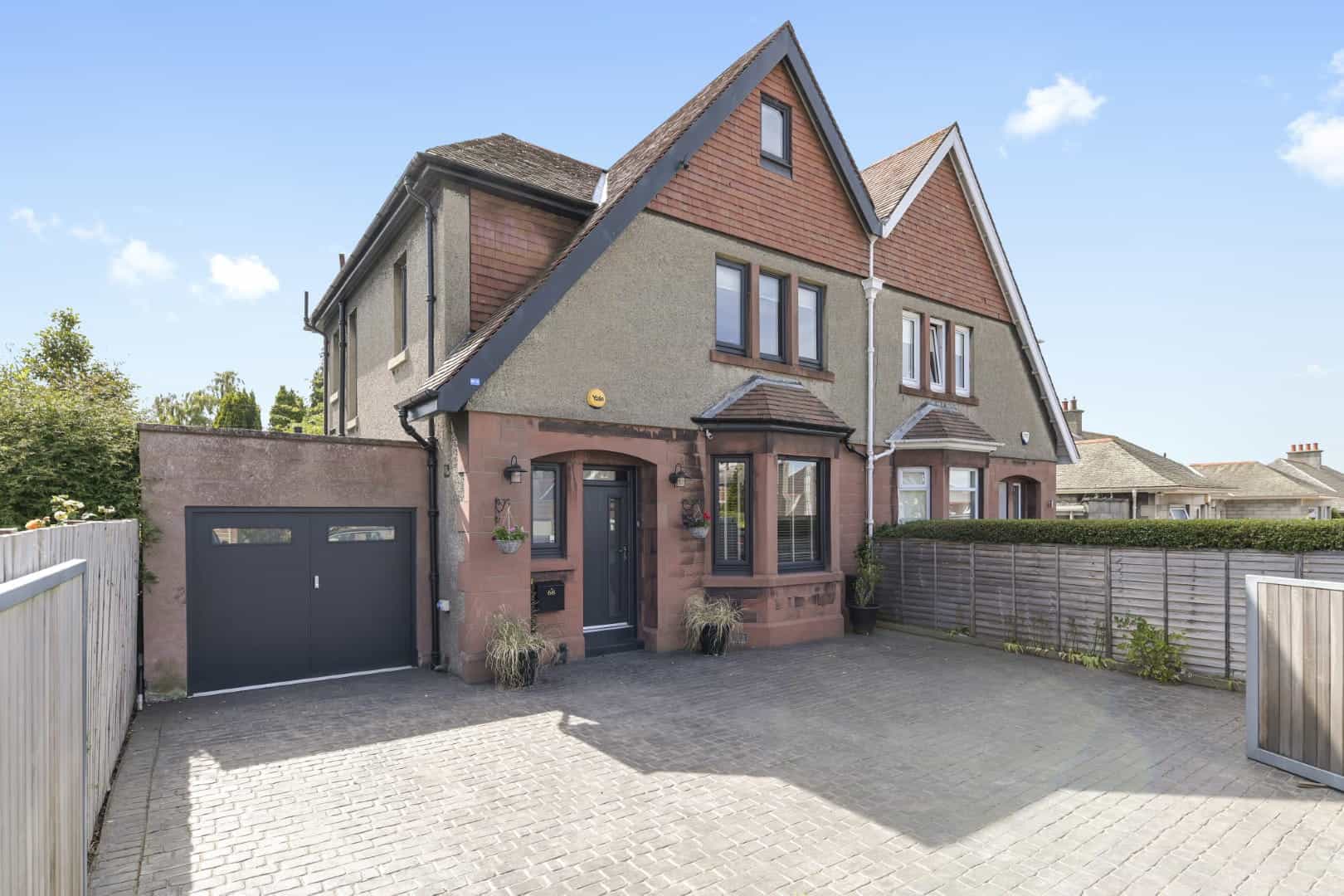 Spacious house with pitched roofs, large windows, and a contemporary driveway, designed by ABC Architecture.
