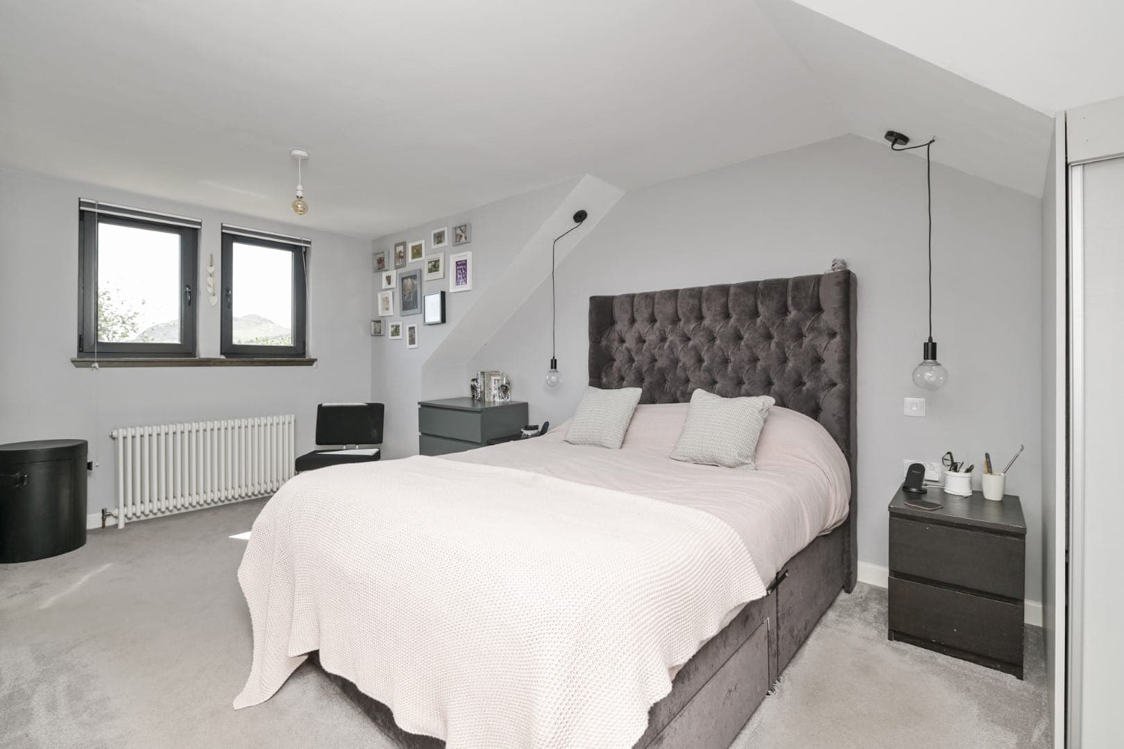 Contemporary bedroom design with grey tones, stylish pendant lights, and personalised wall art.