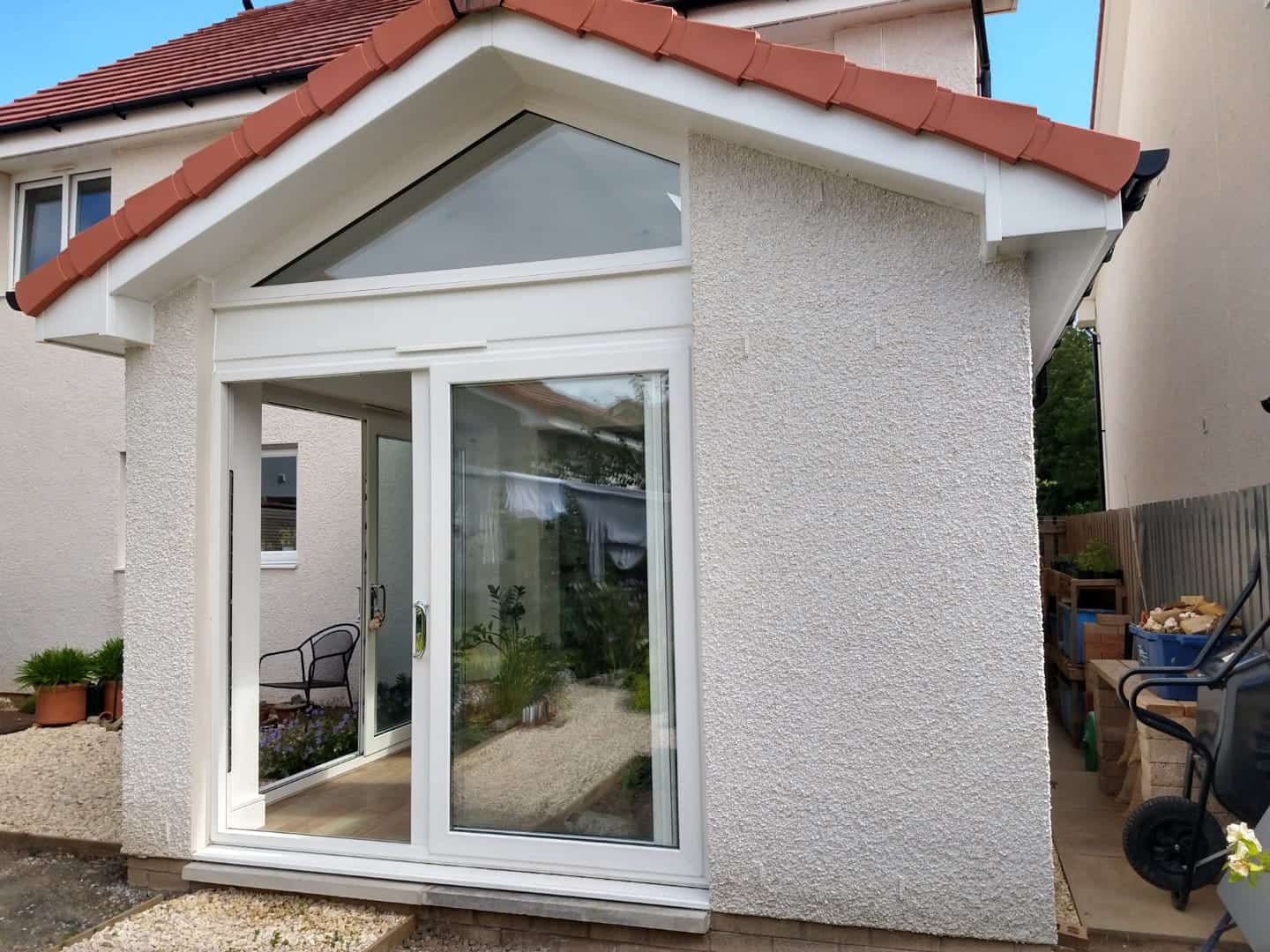 Bright conservatory extension with large glass doors, innovative design, and pitched roof, adding value and space to the home.