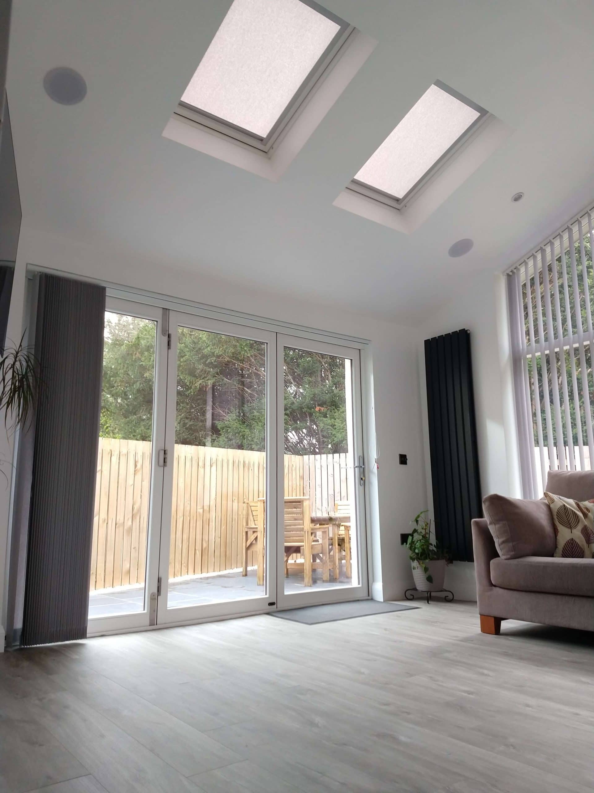 Bright contemporary living space featuring skylights, large glass doors, and stylish interior design.