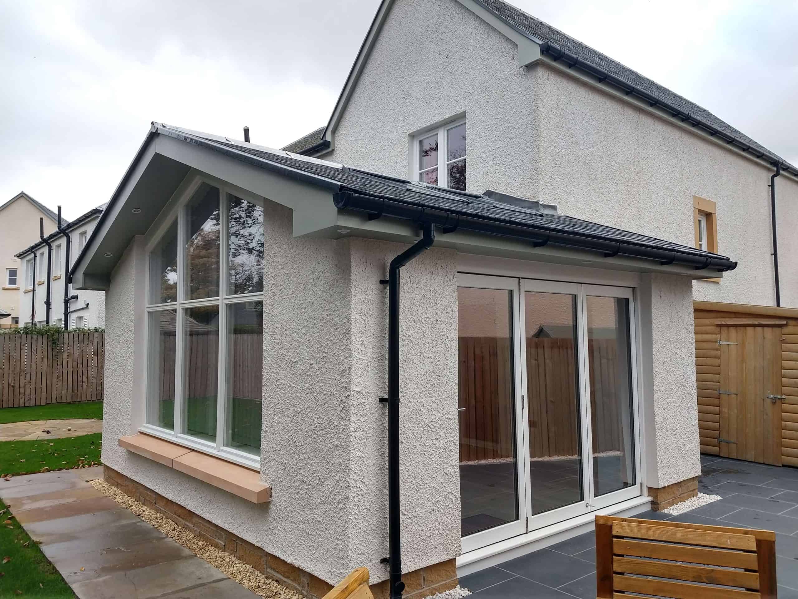 Bright home extension with large bay windows and sliding doors, blending indoor and outdoor living spaces seamlessly.