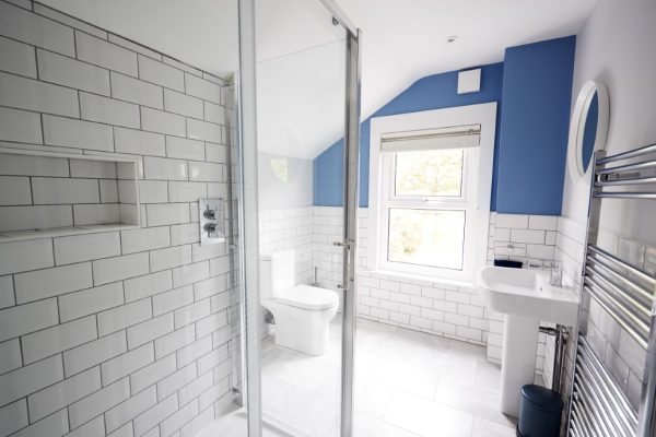 Bright, contemporary bathroom with white subway tiles, blue accent wall, and modern fixtures.