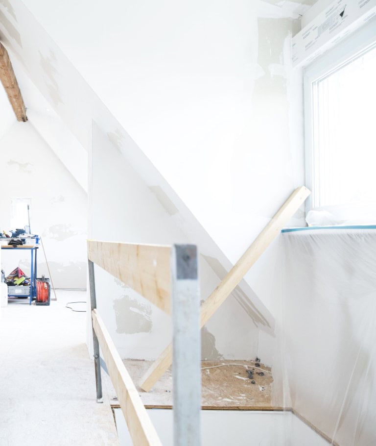 Bright attic space renovation with drywall and timber framing in progress.