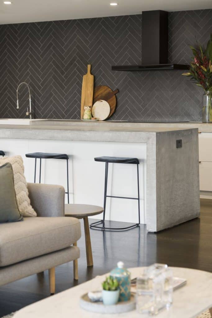 Stylish kitchen with black herringbone tiles, wooden accents, and contemporary bar stools.