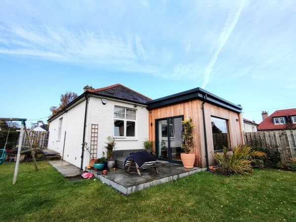 Contemporary garden room extension with timber exterior and large sliding glass doors, designed for outdoor living.