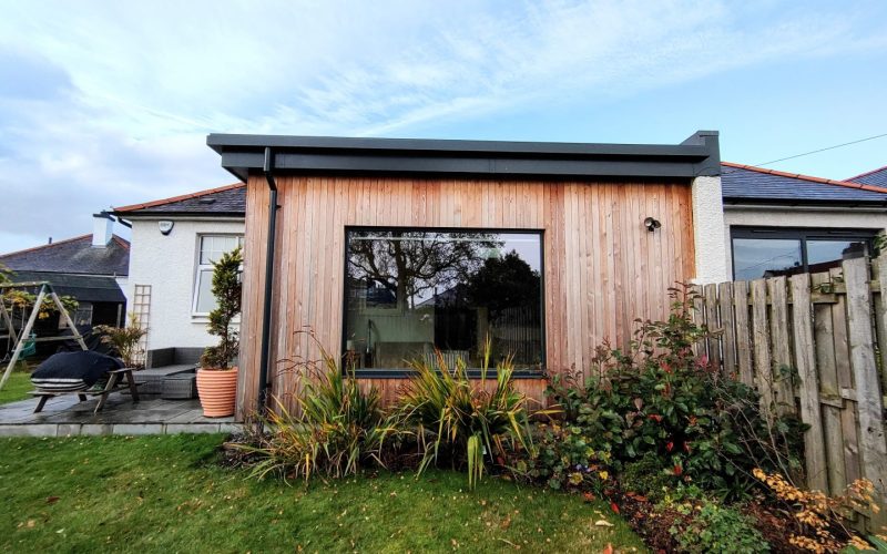 Contemporary garden room with wooden facade and expansive glass window for outdoor living.