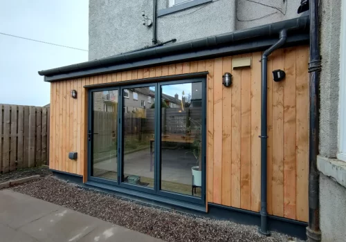 Contemporary garden extension with timber facade, large glass doors, and external lighting for modern outdoor spaces.