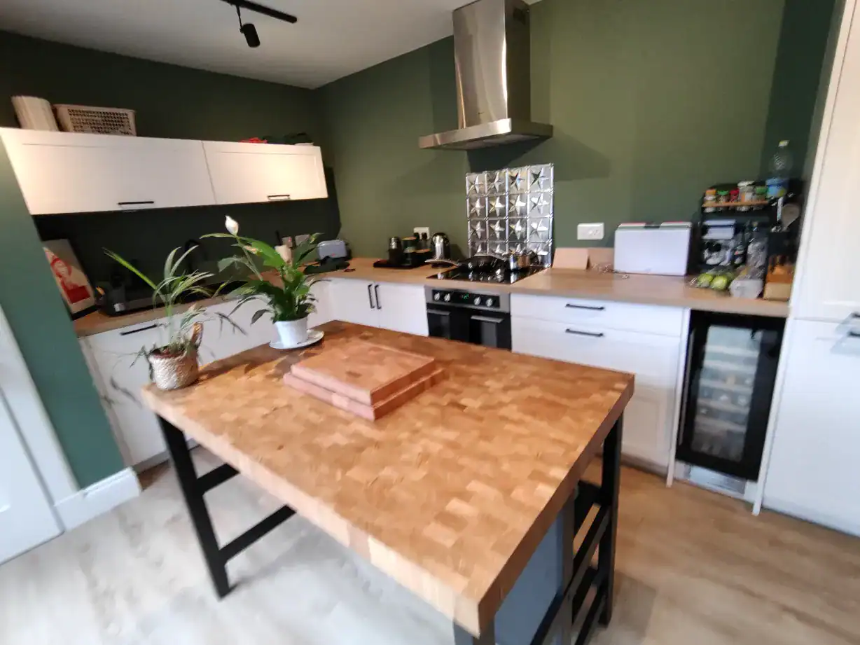 Bright, contemporary kitchen with wooden worktop, cabinetry, and sleek appliances.