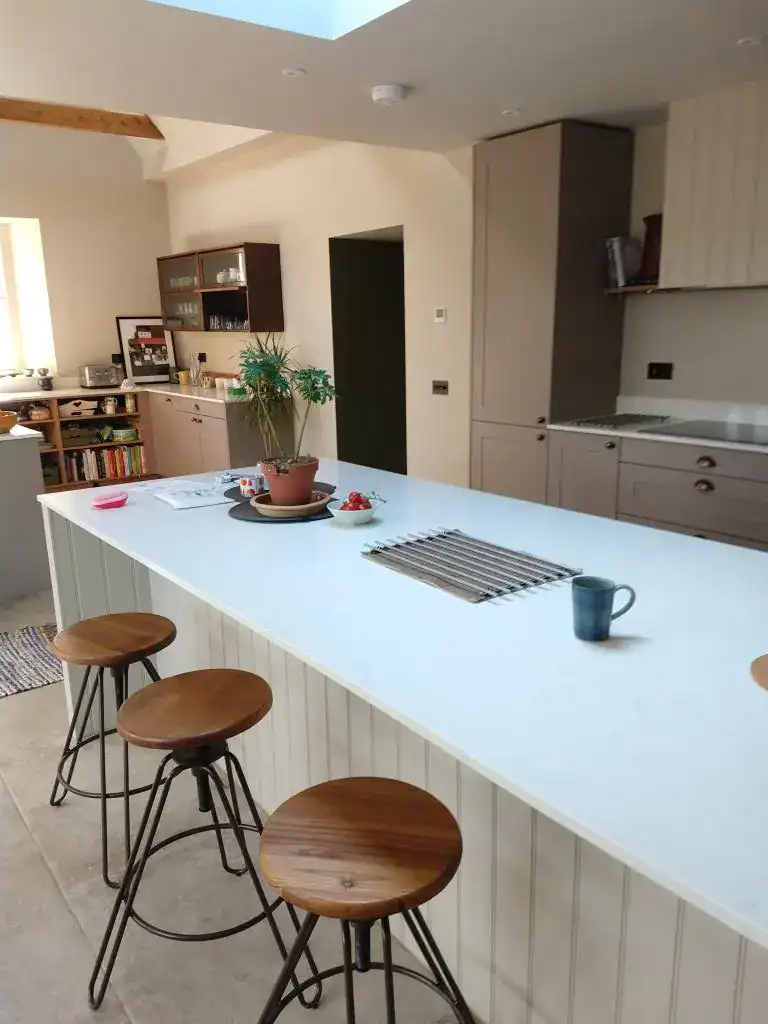 Stylish kitchen with a large white island, wooden bar stools, and contemporary cabinetry. Bright, functional, and inviting for family living.